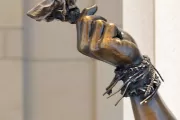 Sculpture detail of a person's hand and arm.