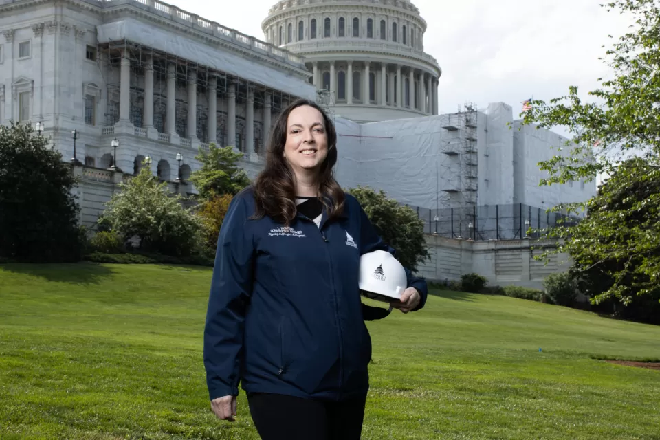 Portrait of a person standing holding a hardhat.