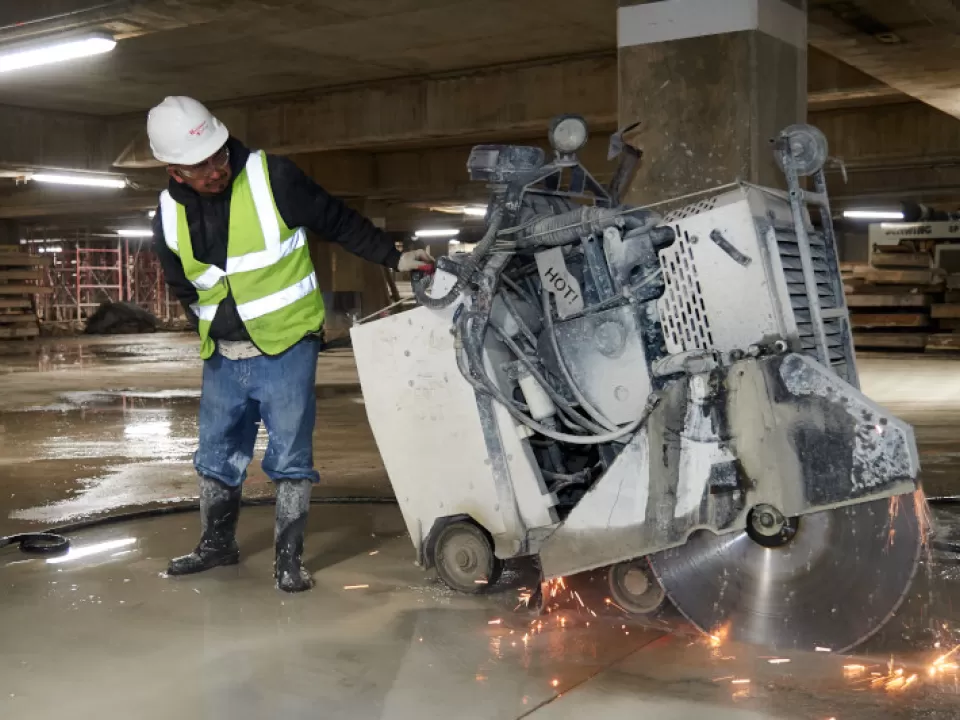 A worker cuts an old concrete slab around columns that cannot be reached by hydrodemolition. 