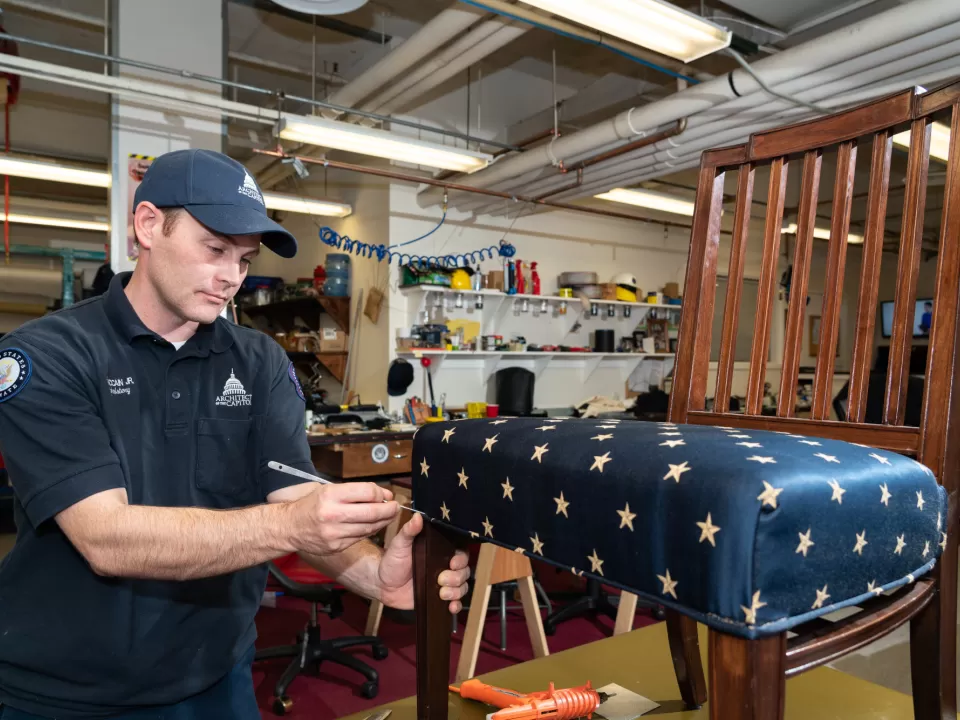 Lowell McCain, Jr., of the Senate Upholstery Branch, works on a historic chair in the Senate upholstery shop.